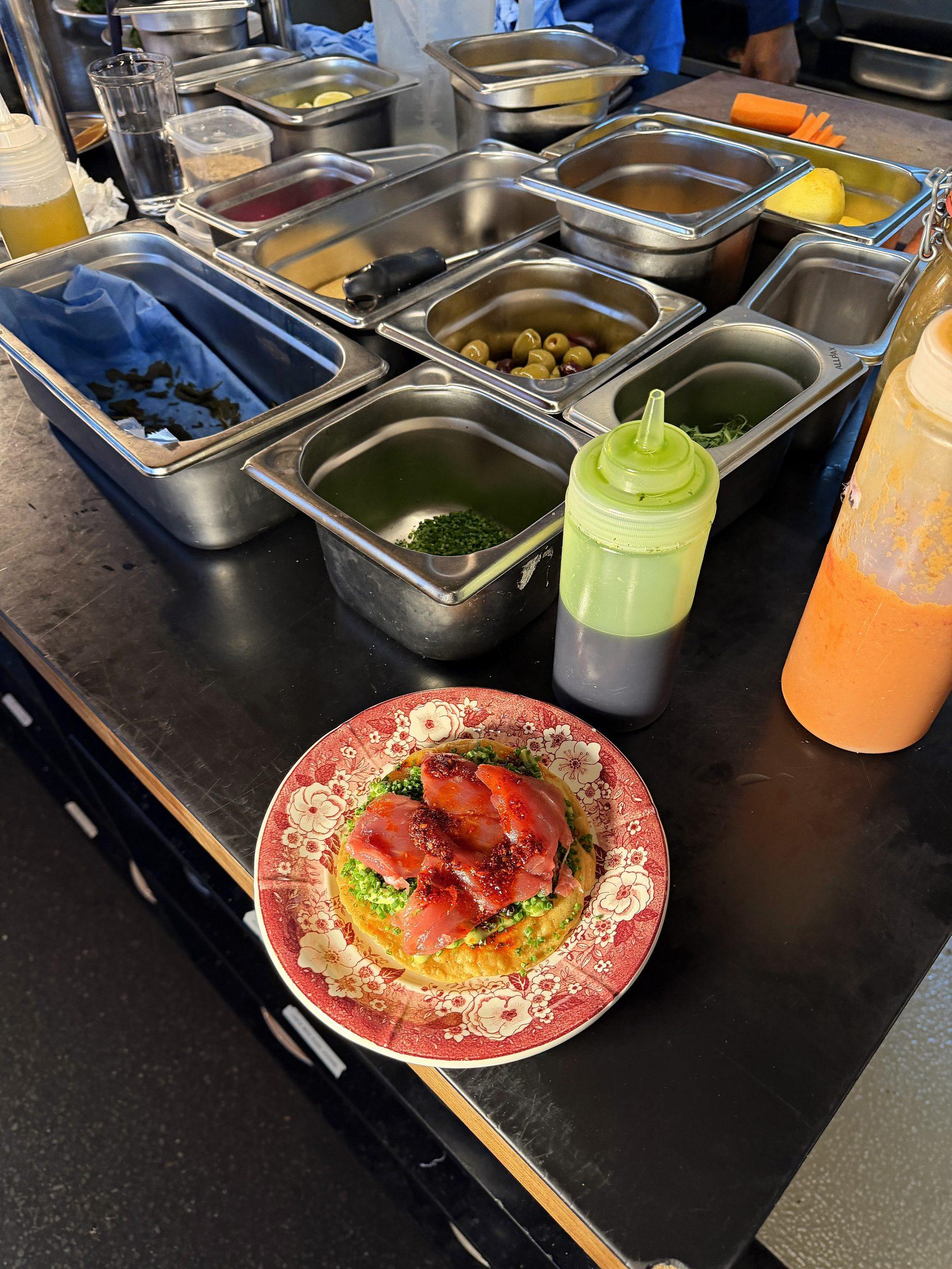 Mise en place in Gastronormbehältern, daneben ein angerichteter Teller
